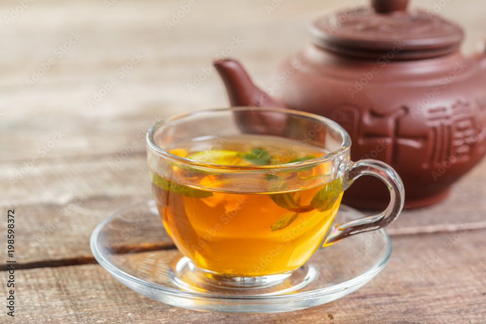 cup of black tea with mint leaves on a wooden table