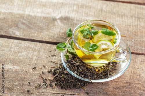 cup of black tea with mint leaves on a wooden table