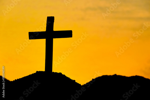 Concept conceptual cross religion symbol silhouette in nature over sunset or sunrise sky