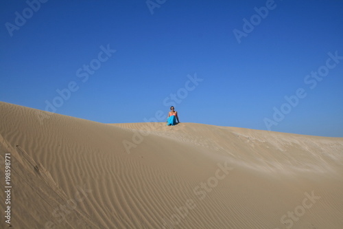 Young woman in blue skirt in sand dunes