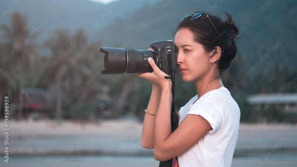 young woman photographer, taking pictures of landscape at sunset