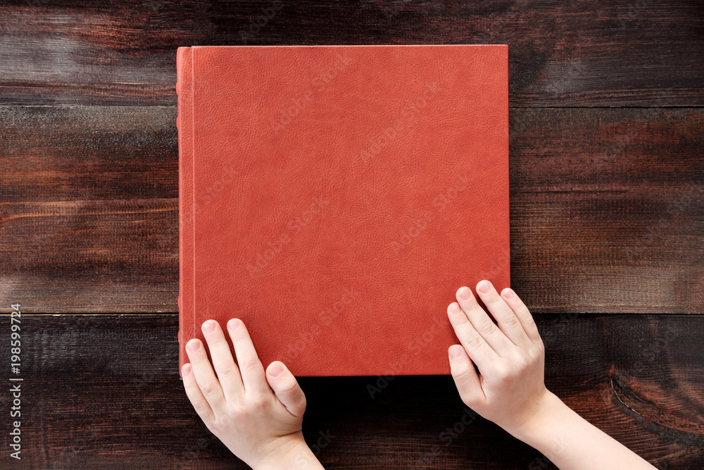 kid holding hands on brown leather covered wedding album or book kid holding hands on brown leather covered wedding album or book