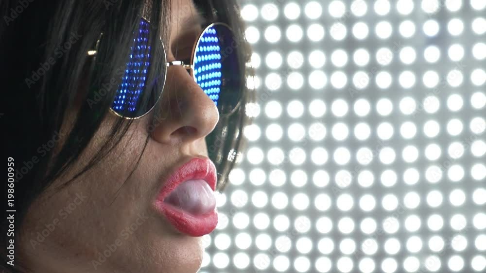 Hot brunette in round sunglasses, chewing gum and blowing a bubble. 4k, slow motion.
