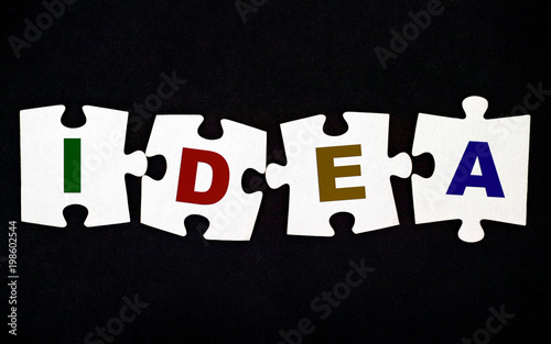 Four pieces of puzzle with letters IDEA on black background