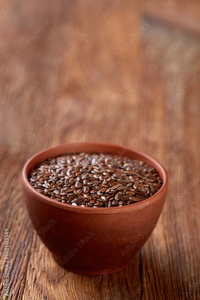 Flax seeds in ceramic bowl on rustic wooden background, top view, shallow depth of field Flax seeds in ceramic bowl on rustic wooden background, top view, shallow depth of field