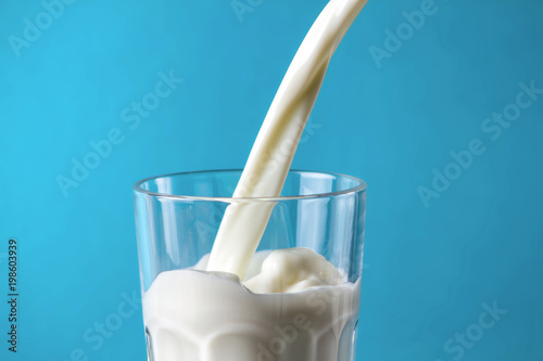 Fluffy milk in a glass on a blue background