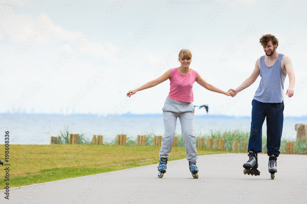 Young couple holding hands while rollerblading Young couple holding hands while rollerblading