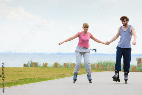 Young couple holding hands while rollerblading