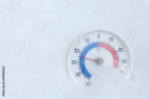 Outdoor thermometer in snow shows minus 24 Celsius degree freezing winter weather concept