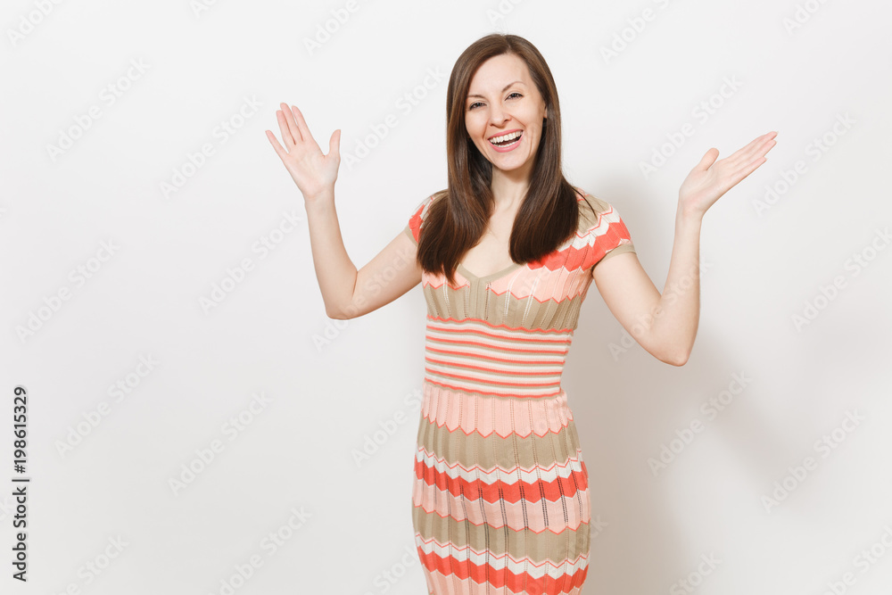 Beautiful young brunette female in light beige and pink patterned dress rejoices, smiling and spread hands with copy space in different directions in studio on white background. Concept of good mood