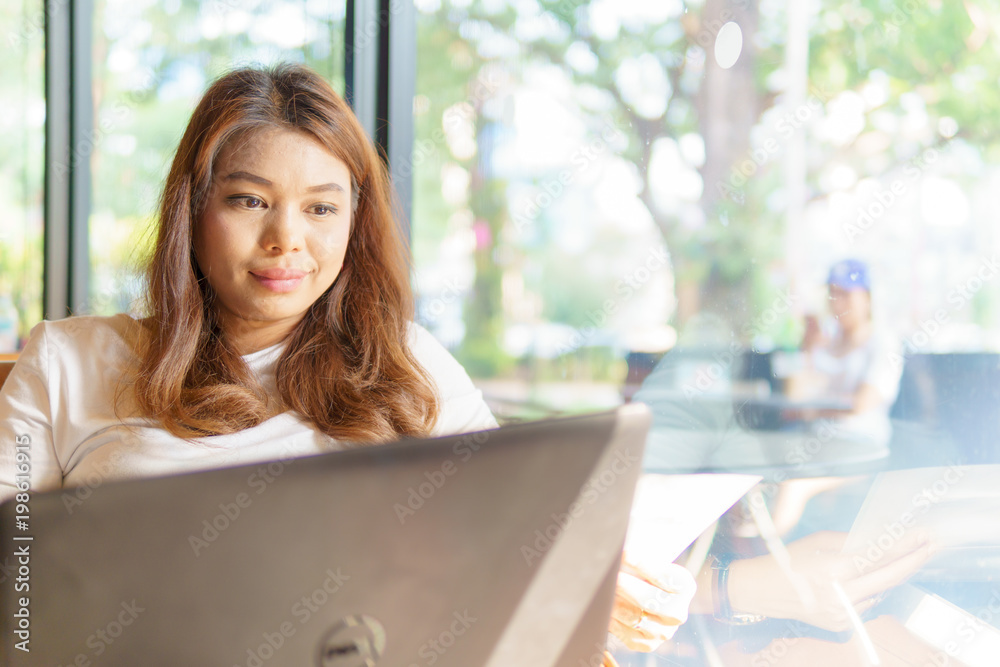 beautiful asian young business woman sitting near transparent window and using laptop for her job at cafe or coffee shop. business concept. beautiful asian young business woman sitting near transparent window and using laptop for her job at cafe or coffee shop. business concept.