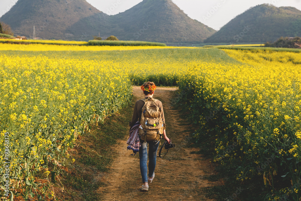 Woman tourist walk through beautiful rapeseed fields in countryside
