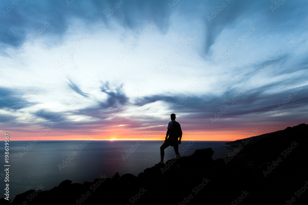 Celebrating or meditating man looking at sunset ocean