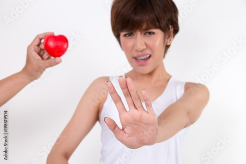 Disappointed woman rejecting the red heart of her boyfriend. Isolated on white background. Studio lighting.