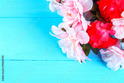 Pink peonies on a blue wooden table. Postcard for the holiday. Copy the space. Top view.