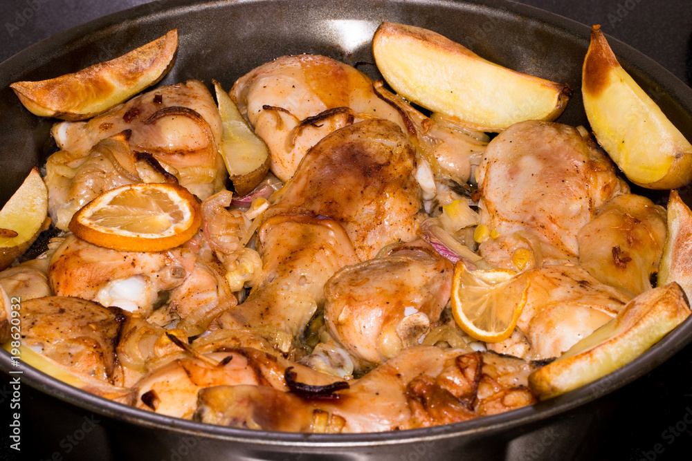 Chicken legs with potatoes are fried in a pan with sauce closeup Chicken legs with potatoes are fried in a pan with sauce closeup