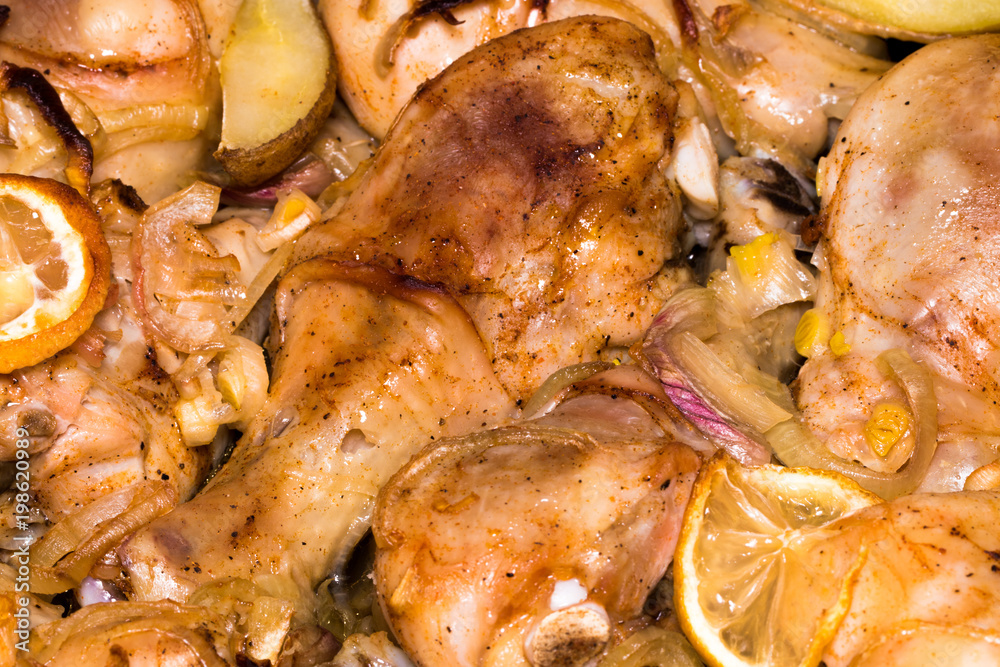 Chicken legs with potatoes are fried in a pan with sauce closeup Chicken legs with potatoes are fried in a pan with sauce closeup