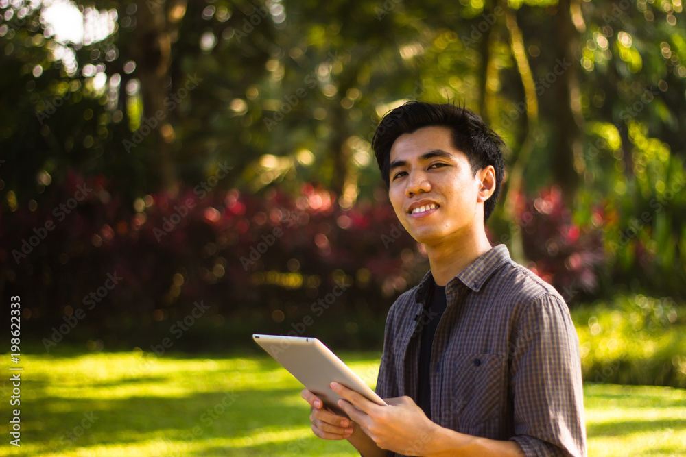 Fototapeta premium Closeup shot of smiling young Malay man using tablet computer