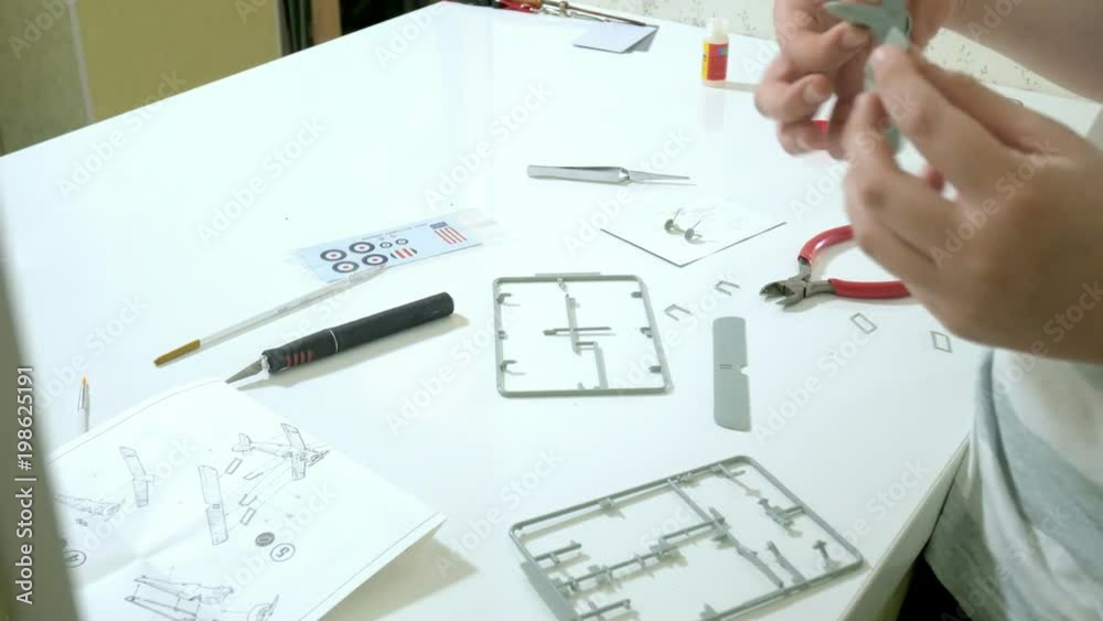 The boy creates a plastic model airplane, an exact copy, from the designer The boy creates a plastic model airplane, an exact copy, from the designer
