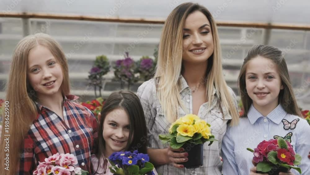 Smiling four girls with flowerpots in hands looking at camera Smiling four girls with flowerpots in hands looking at camera