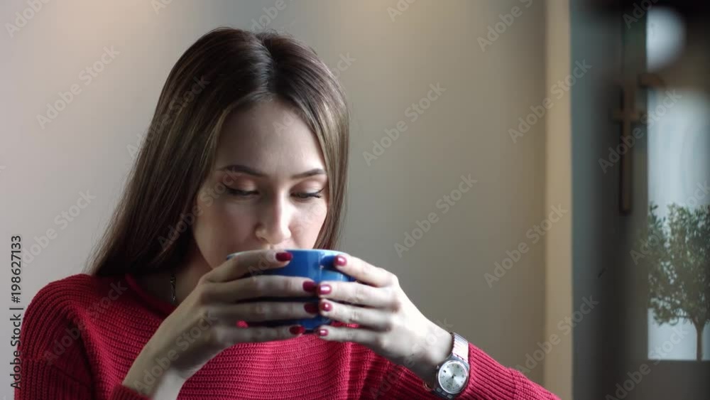 Beautiful Young Girl Drinks Coffee and Smiles. The girl is smiling at the camera
