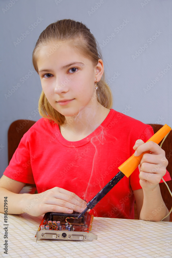 A teenage girl soldering an electronic card