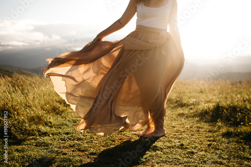 Fotografie woman wearing a long skirt blowing in the wind in the summer sun