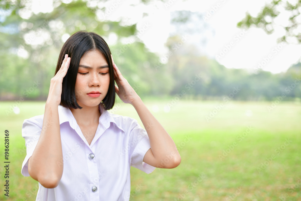 Education Concepts. Beautiful young Asian girl is thinking seriously. Beautiful Asian students are thinking in the garden. Beautiful young student is headache in the garden. Education Concepts. Beautiful young Asian girl is thinking seriously. Beautiful Asian students are thinking in the garden. Beautiful young student is headache in the garden.