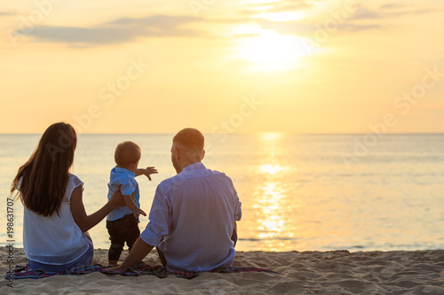Family on the beach concept, Caucasian boy siting and holding sand on the tropical beach in sunset time