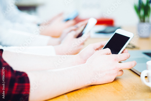 Young casual business people using smart phone for social networking