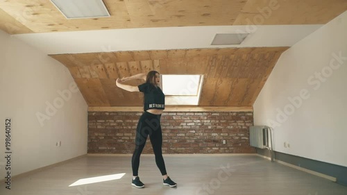 beautiful athletic girl in black dancing vogue or hip hop and jumping on brown background. Long shot. Wide shot.
