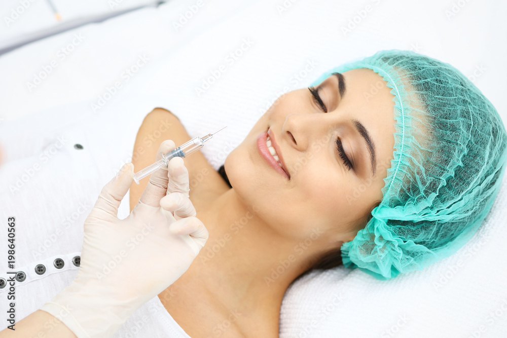 Professional cosmetologist making injection in face, lips. Young woman gets syringe with filler for face contouring or augmentation. Face aging, rejuvenation and hydration procedures