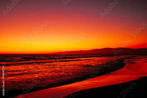 A beautiful Santa Monica beach coastline  at sunset with stunning sky and its relfecting light on the ocean waves below.
