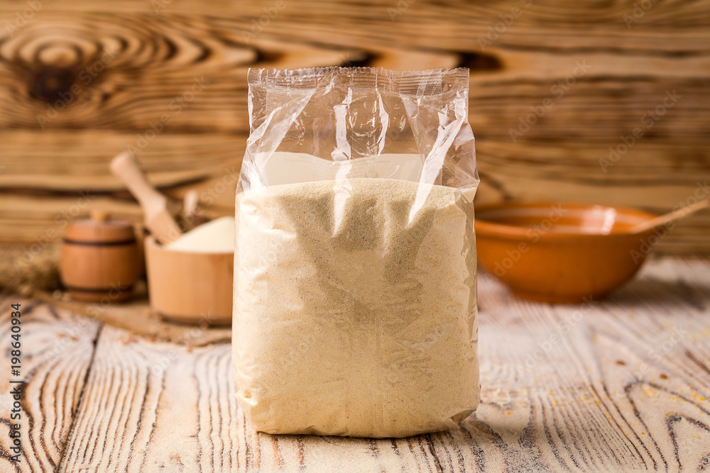 semolina in packing and bowl on a wooden background. Healthy dietary cereals concept.