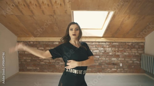 beautiful athletic girl in black dancing vogue or hip hop and jumping. Mid shot