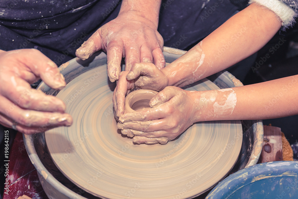 Little child learns how to sculpt a ceramic plate on a potter's wheel. Close-up of a child's hand. Little child learns how to sculpt a ceramic plate on a potter's wheel. Close-up of a child's hand.