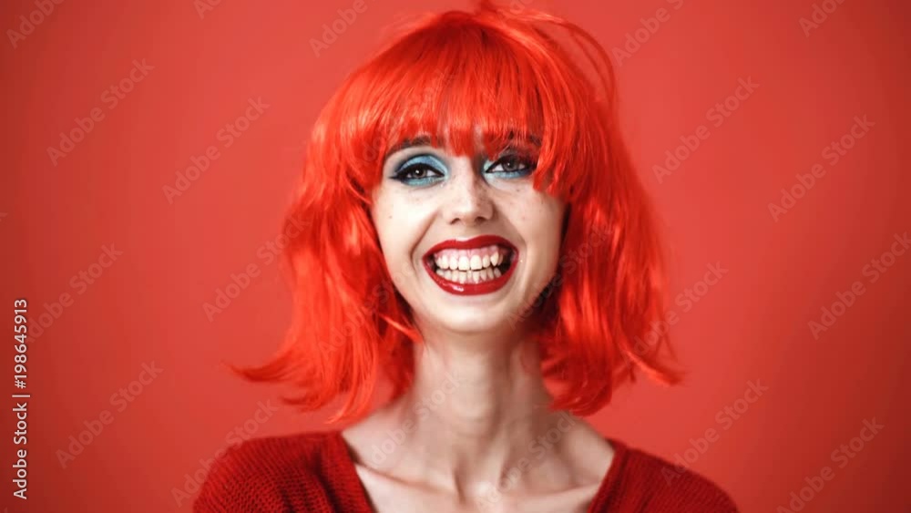Beautiful girl in red wig. A young girl in the studio on a background. Stylish girl wearing a red wig. Beautiful girl in red wig. A young girl in the studio on a background. Stylish girl wearing a red wig.