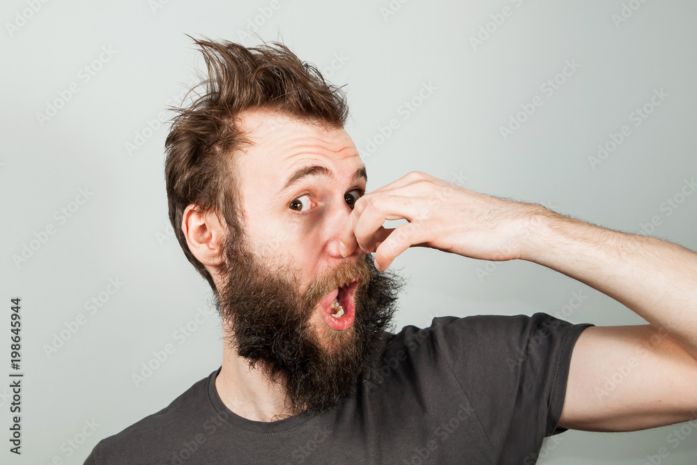 Fototapeta premium Young baerded guy closing nose from a bad smell.