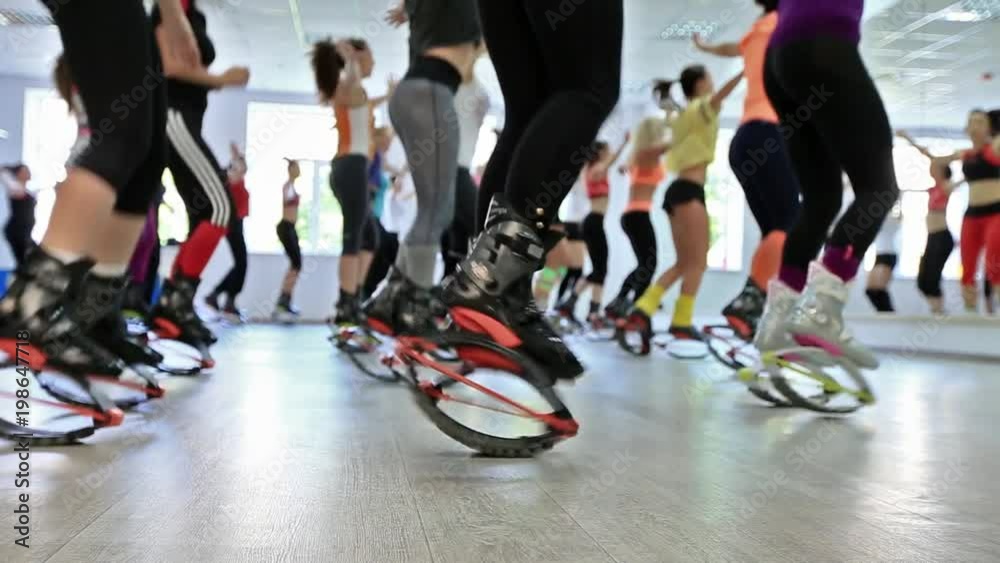 Group of young caucasian women doing fitnes exercises with kangoo jumps shoes in a gym.