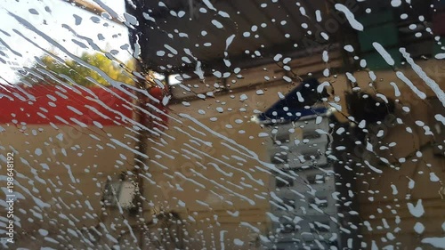 close up of front mirror surface of car cover with car wash soap in the car cleaning center.
