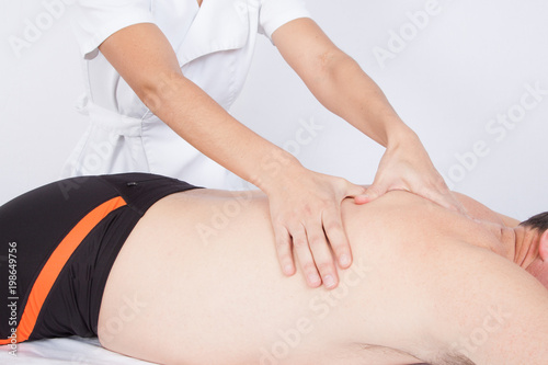 Man relaxing on massage table receiving massage by woman hands