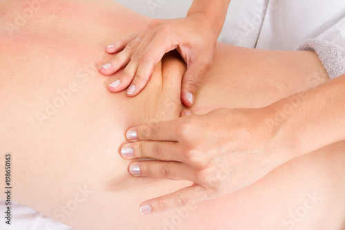 Man receiving back massage from woman masseur in spa