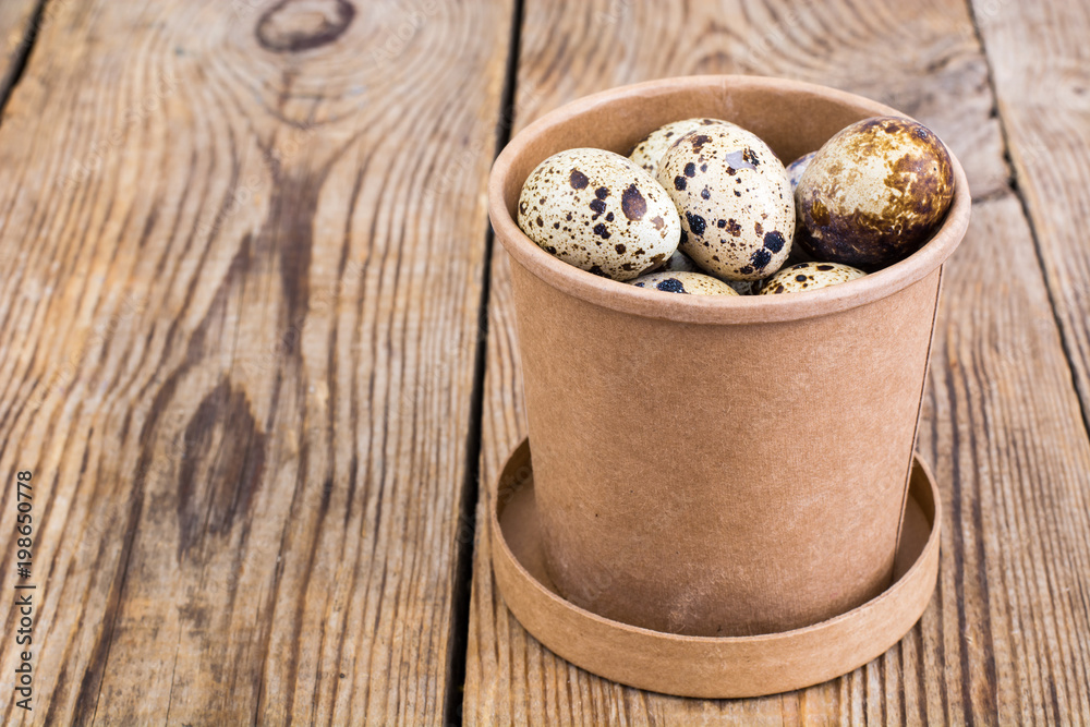 Quail eggs in cardboard box on wooden table Quail eggs in cardboard box on wooden table