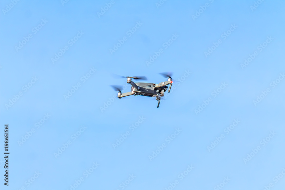drone quad copter with high resolution digital camera flying hovering in the blue sky. drone quad copter with high resolution digital camera flying hovering in the blue sky.