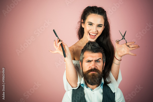 Woman with razor, scissors cut hair of man.