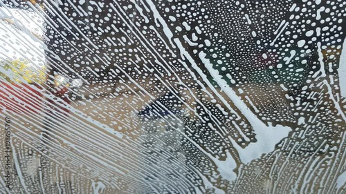 close up of front mirror surface of car cover with car wash soap in the car cleaning center.