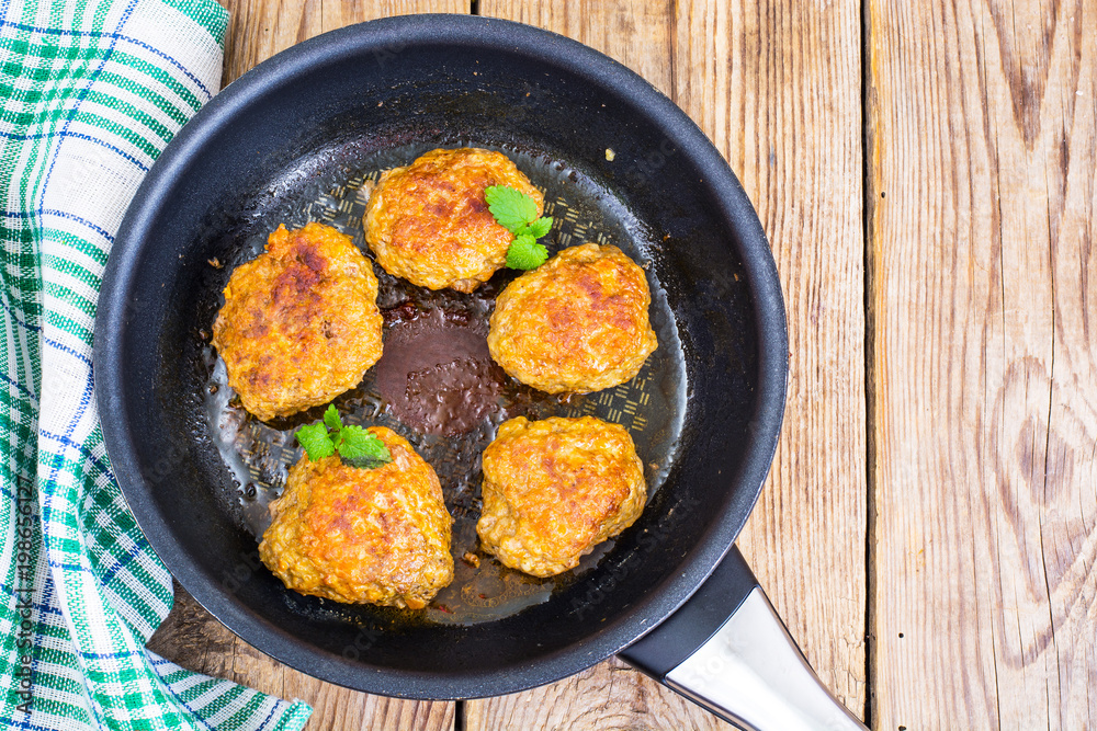 Frying pan with fried cutlets on wooden table Frying pan with fried cutlets on wooden table