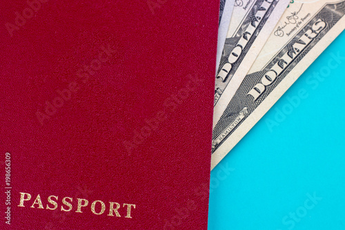 red passport with dollar bills on blue background. Concept of traveling