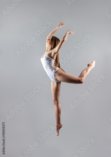 a young slender girl gymnast jumps high in the dance.