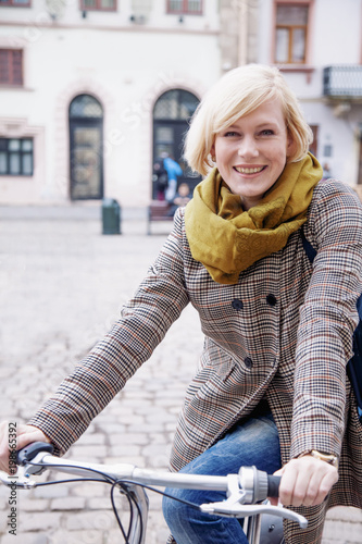 Active fashionable happy beautiful young blonde woman with bike in the old European city. Lifestyle, style and tourism concept.